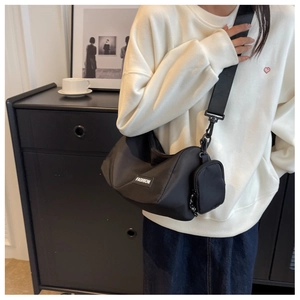 Detail of black nylon crossbody bag with side pouch accessory and wide shoulder strap