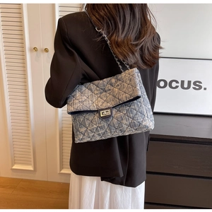 Close-up of blue denim quilted bag with silver twist-lock and metal chain strap