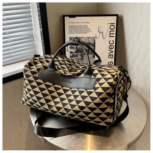 Détail d'un grand sac de voyage en toile à motifs géométriques et poignées en cuir