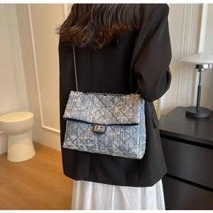 Close-up of blue and white tweed crossbody bag with silver chain strap and metal clasp