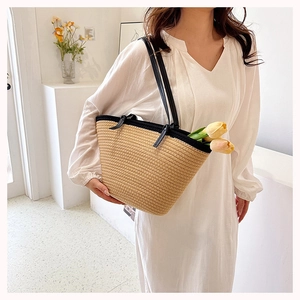 Detail of hand-woven straw tote bag with black leather straps and spacious interior