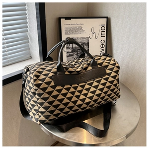 Vue détaillée du motif géométrique tissé et des finitions en cuir noir du sac de voyage