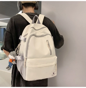 Detail view of large beige and grey backpack with multi-pocket design and cute donkey charm