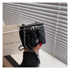 Nahaufnahme der schwarzen gesteppten Mini-Tasche mit Silber-Kamelie und Kettenriemen