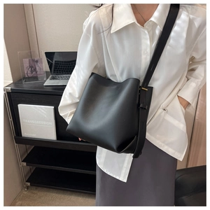Detail of a matte black bucket bag with adjustable strap in a modern minimalist setting