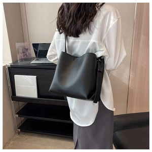 Model wearing a high-quality black leather bucket bag with a stylish shoulder strap
