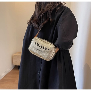 Detail of golden textured crossbody bag with SMILEDT letter print and brown strap