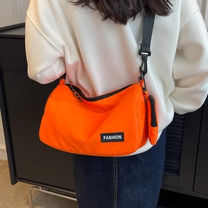 Large orange nylon crossbody pillow bag with adjustable strap and small coin purse