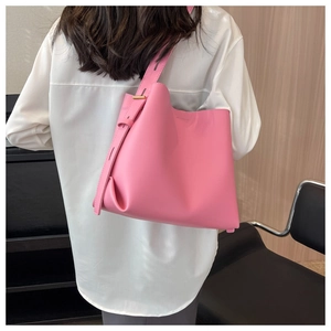 Detail of pink bucket bag featuring a wide adjustable shoulder strap and gold hardware