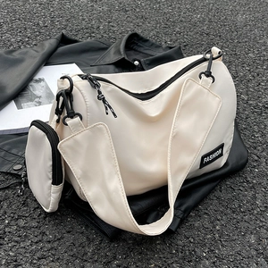 Large beige nylon shoulder bag with fashion tag and small pouch on dark background