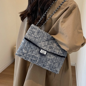 Blue tweed quilted chain bag with silver twist lock shown on a tan trench coat