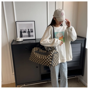 Détail d'un grand sac de voyage en toile avec motifs géométriques et anses en cuir