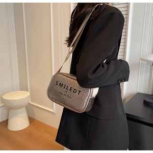 Detail view of metallic bronze crossbody bag with textured pleats and SMILEDT logo strap