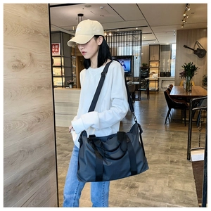 Dunkelgraue Oxford-Stoff-Reisetasche mit verstellbarem Gurt am Model getragen