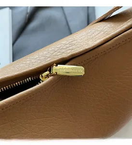 Close-up of golden metal zipper hardware on brown lychee grain leather bucket bag