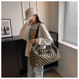 Détail du sac de voyage en toile avec motifs géométriques et écusson en cuir
