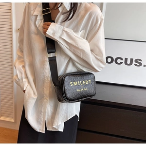 Detail of black leather crossbody bag with wide strap and yellow letter printing