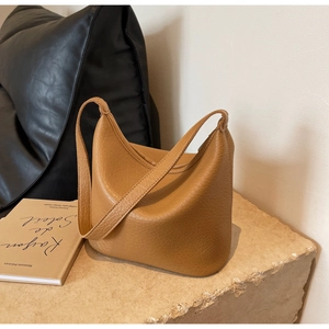 Close-up of pebble grain brown leather bucket bag on minimalist stone display