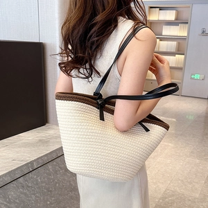 Large beige woven tote bag with black leather shoulder straps for summer commuting