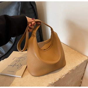 Detail of camel bucket bag with lychee pattern faux leather on stone texture surface
