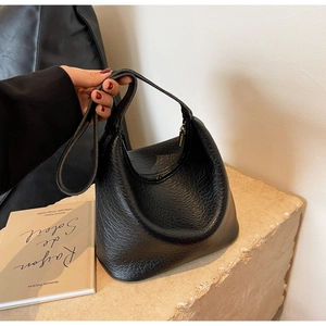 Close-up of black lychee texture leather on a minimalist hobo bucket bag with zipper