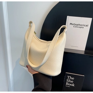 Close-up of the textured off-white pebble leather surface on a minimalist bucket handbag