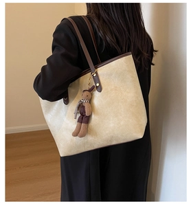 Détail d'un grand sac cabas beige avec anses marron et un pendentif lapin mignon sur le côté