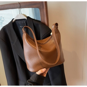 Detailed texture of brown pebbled leather shoulder bag with minimalist crescent design