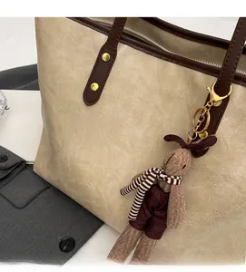 Détail du sac cabas beige avec anses en cuir marron et charm lapin tricoté