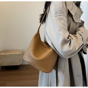 Close-up of a camel lychee grain leather bucket bag featuring soft texture and minimalist strap