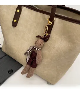 Gros plan d'un porte-clés lapin tricoté marron avec écharpe rayée sur un sac cabas