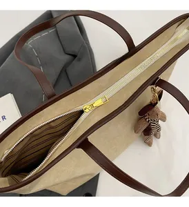 Détail de la fermeture éclair dorée et doublure rayée du grand sac fourre-tout beige