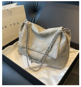 Macro detail of grey leather crossbody bag with chain strap in elegant gift box