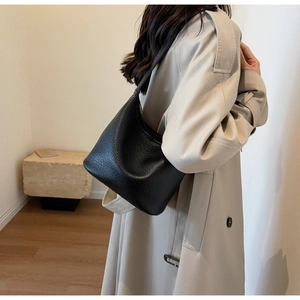 Detailed back view of a minimalist black pebbled leather hobo bag on a model shoulder
