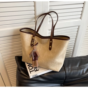 Détail du cabas marron clair avec des anses marron foncé et un pendentif lapin