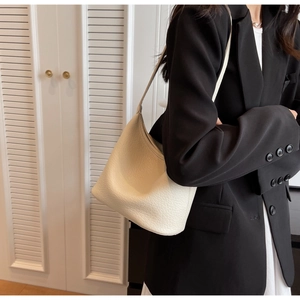 Detail of a minimalist off-white pebble leather hobo bag with seamless shoulder strap