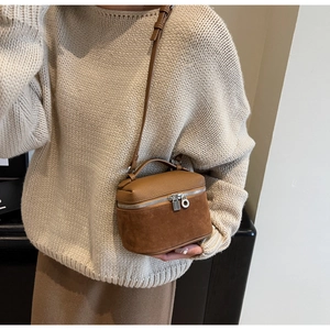 Close-up of brown textured leather and suede crossbody bag with silver lock zipper detail