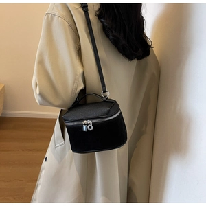 Detail of black bucket bag featuring litchi grain and suede stitching with silver hardware