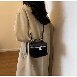 Detail of black matte and lychee leather bucket bag with silver zippers shown on model