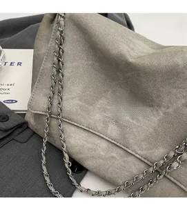 Detail of grey textured chain shoulder bag with metal woven strap and flap closure