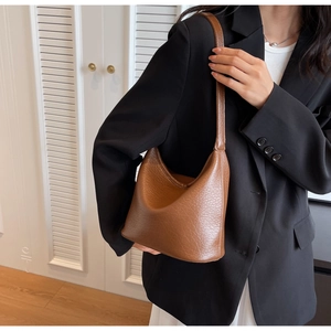 Detailed texture of dark brown lychee grain leather on a minimalist shoulder bucket bag