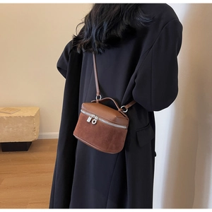 Detailed view of brown contrast leather crossbody bag on a model in a black coat