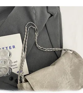 Detail shot of silver metal and leather braided chain strap on a grey shoulder bag