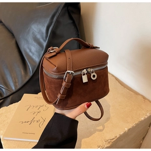 Detail of retro brown box-style handbag with patchwork leather, silver lock, and charms