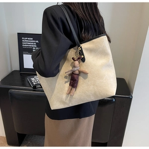 Détail du sac cabas crème avec texture craquelée, poignées noires et pendentif lapin
