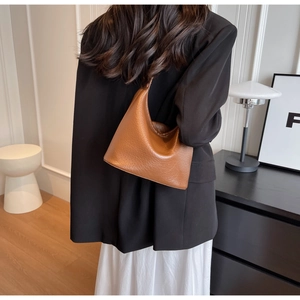 Detailed texture of caramel brown lychee grain leather on a soft hobo bucket shoulder bag