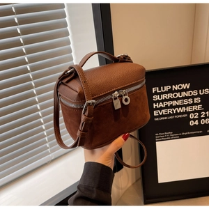 Close-up of brown textured leather and suede bucket bag with metallic zipper and gold hardware