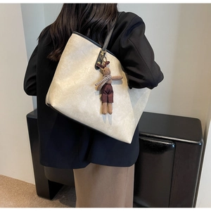Détail du sac cabas crème avec texture froissée, bandoulière noire et breloque lapin brun