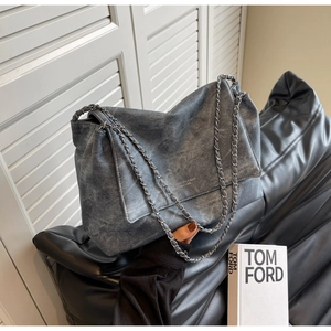 Detail of grey chain shoulder bag featuring retro washed denim texture on leather sofa