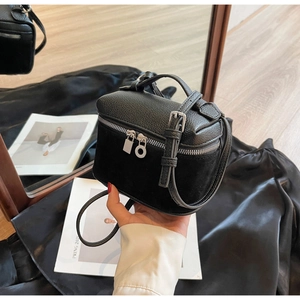 Dettaglio di una borsa in pelle nera con cerniera ad anello in argento e chiusura a scatto